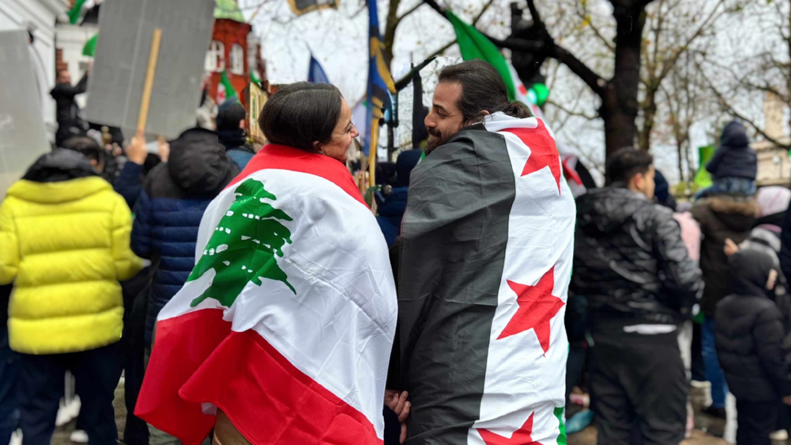 Janay and Habak at an outdoor event with their respective flags draped over their shoulders